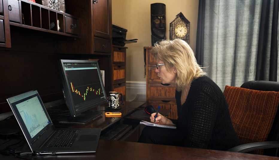 profile of mature woman seated in home office reacting to her sinking portfolio numbers displayed on a graph online due to the coronavirus in 2020