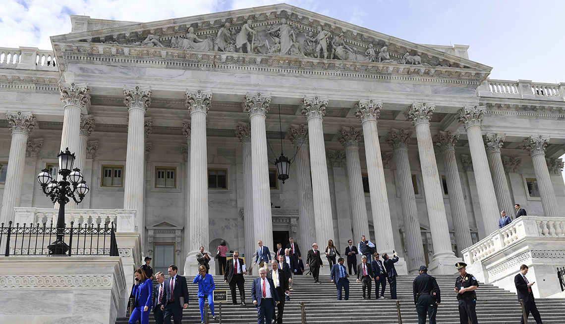 low angle of exterior of Capitol building with people in business suits walking down steps