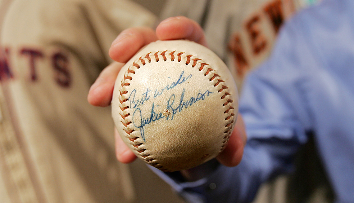 A baseball signed by Jackie Robinson is held up for view at a sports memorabilia auction