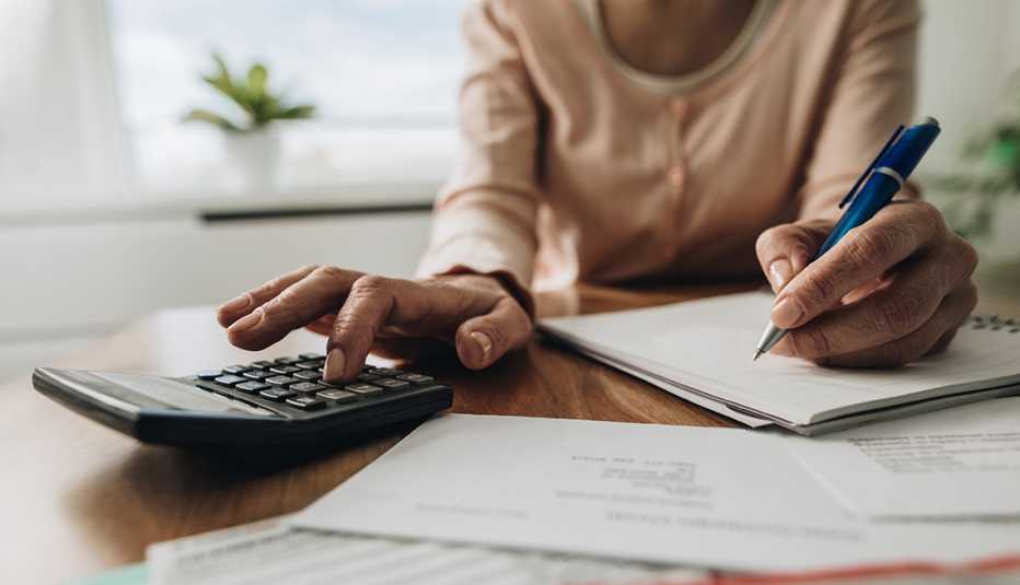 Close up of woman using calculator while going through bills and finances