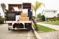 Flatbed truck with furniture and television parked at curb
