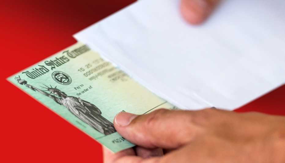 Person sliding a Social Security check out of a white envelope