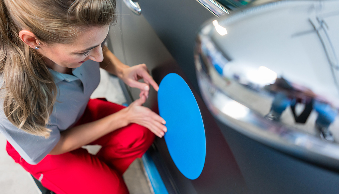 Woman putting sticker with company slogan on a car