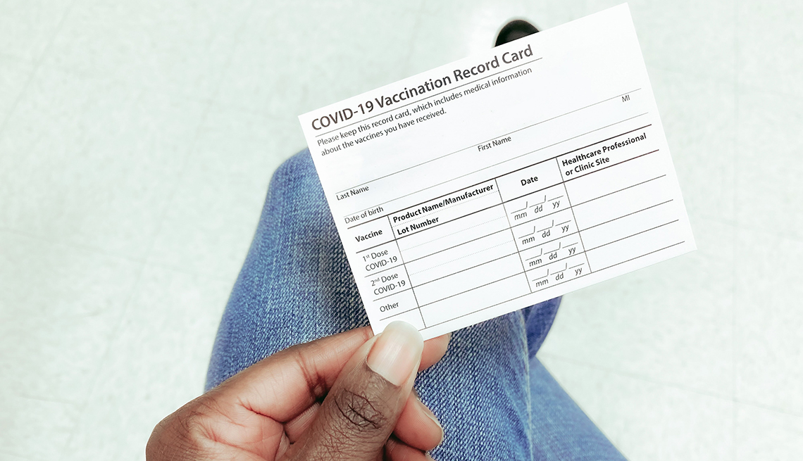 High angle view of unrecognizable black woman holding COVID-19 vaccination record card
