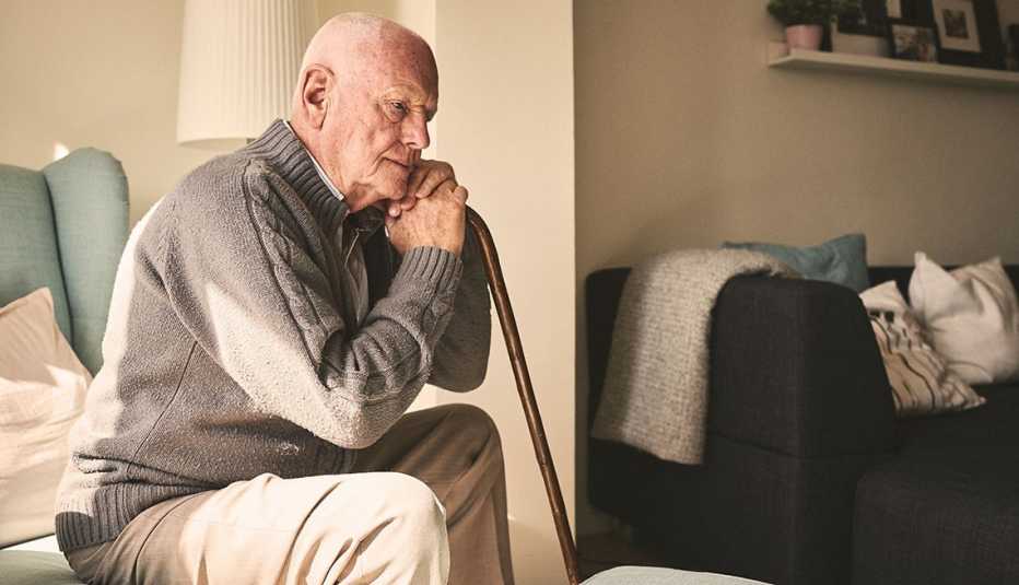 Man sitting alone holding a cane looking sad
