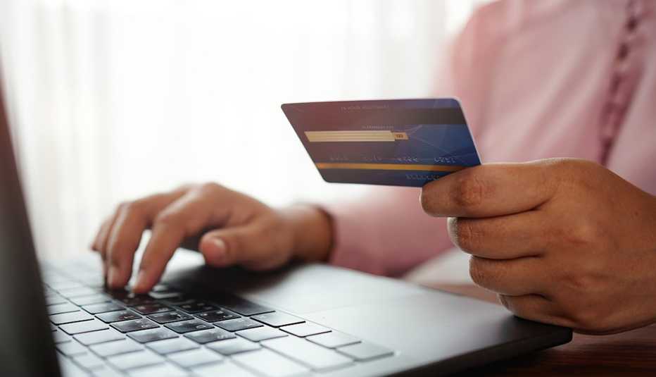 Hands holding a credit card and using the laptop for online shopping and online payment via the internet. Technology concept.