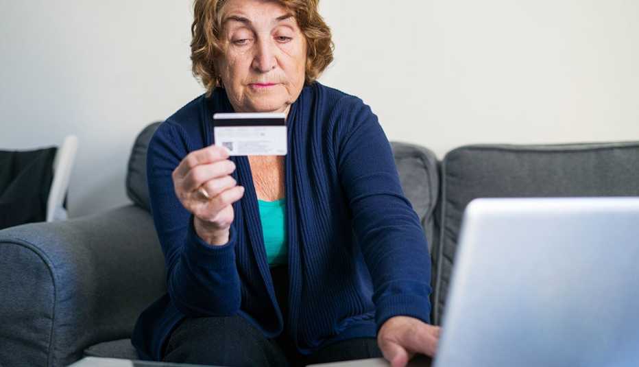 woman on couch with credit card and laptop