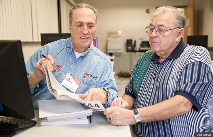 Tax-Aide volunteer Jim Gonzales goes over tax documents with Ray Jimenez
