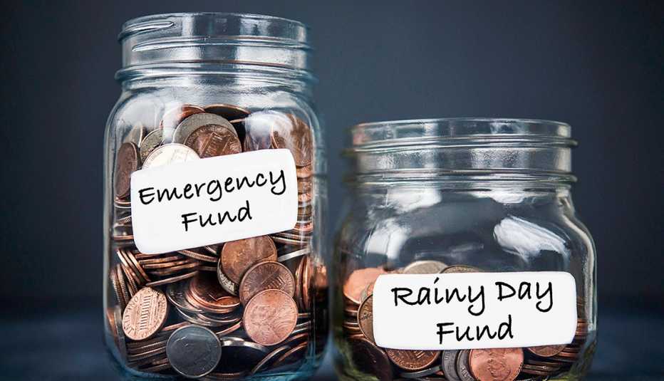 two jars filled with coins. One jar is larger and is labeled emergency fund, the other jar is smaller and contains fewer coins. it is labeled rainy day fund