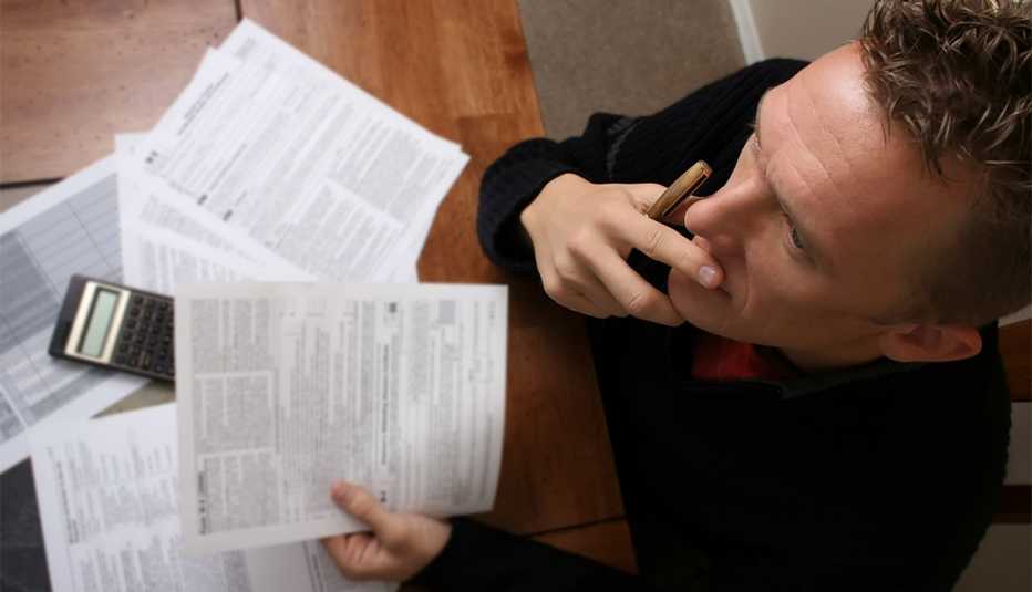 A birds eye view of a man reading the IRS instructions as he is doing his taxes