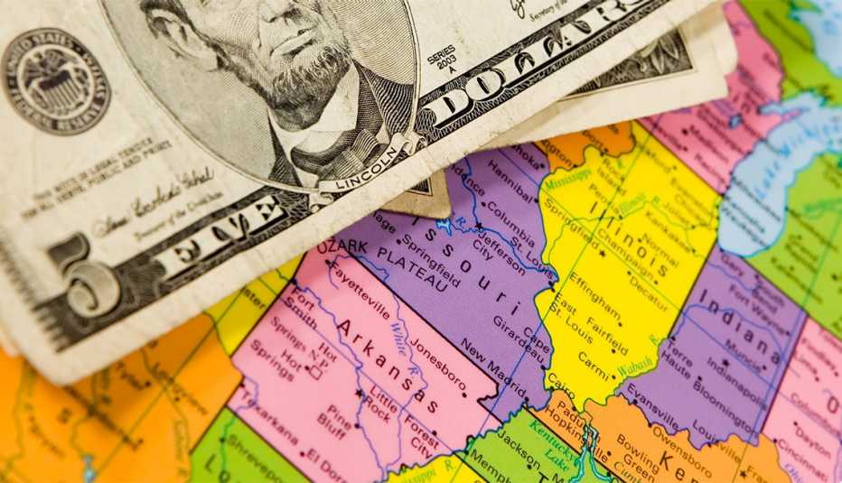 U.S five dollar bills on top of a close up portion of a map of American states. 
