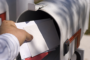 Male human hand pulling white envelopes from outdoor mailbox