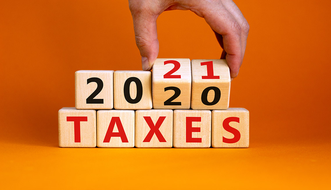 a hand reaching into the top of the photo is  flipping wooden cubes that spell out 'Taxes 2020' to 'Taxes 2021' 