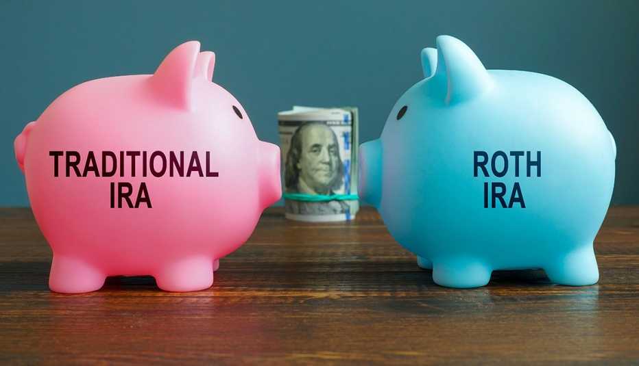 face-off between a pink piggy bank labeled "Traditional IRA" and a blue piggy bank labeled "Roth IRA" with  a roll of money behind them
