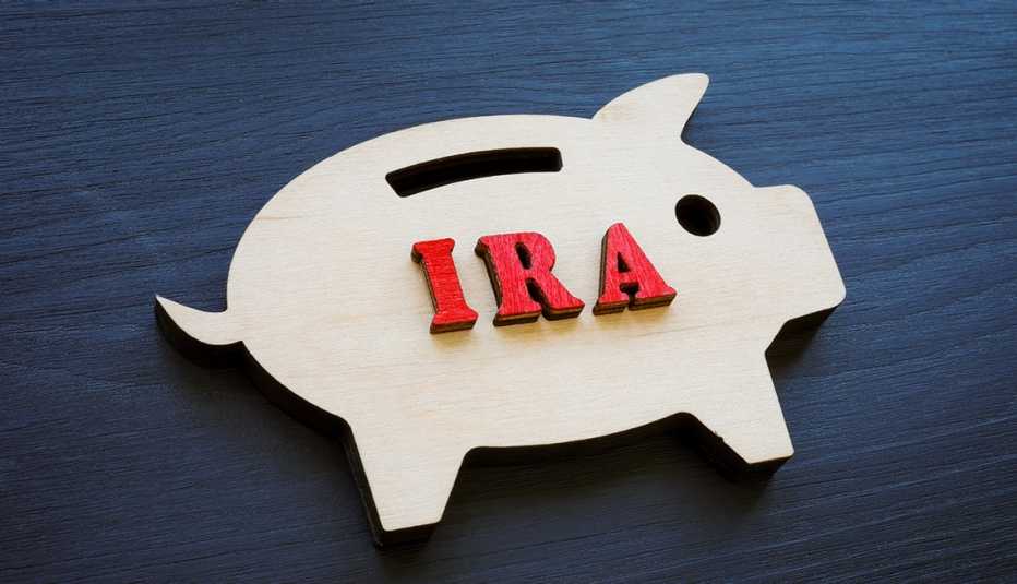 A flat wooden piggy bank on a dark background is labeled IRA.