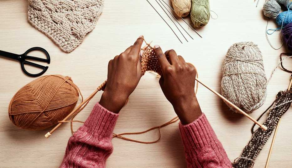 a woman's hands knitting on a white table