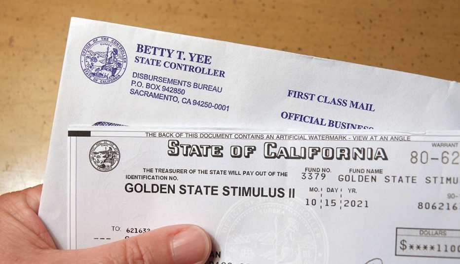 Close up of hand holding a Golden State Stimulus check sent out by the State of California 