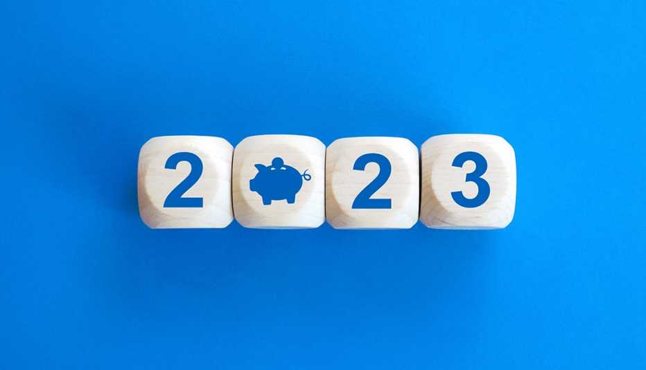 pale wood dice cubes with the numbers 2023 are set against bright blue background with the zero shaped like a piggybank