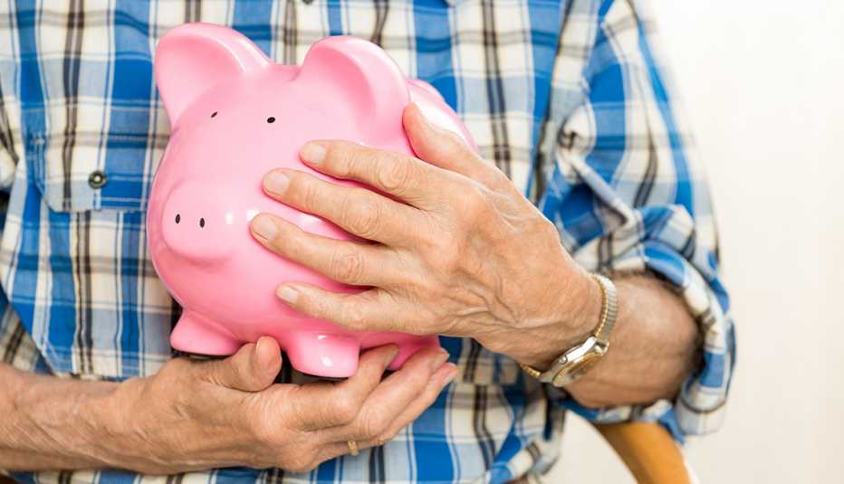 close up of hands holding a piggy bank protectively close to the chest