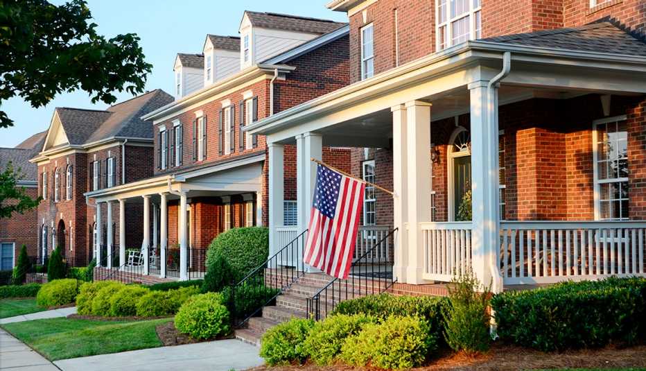 A residential street of brick homes with an American Flag hanging from the front of one home