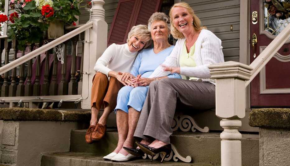 three women sitting on the stairs in front of house