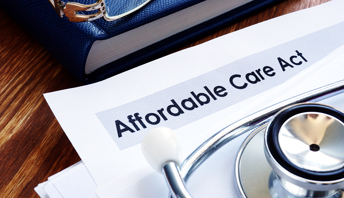 Affordable Care Act paperwork with a blue book and a stethoscope next to it