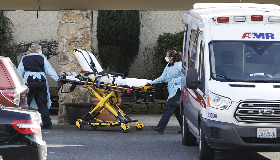 Two people move a stretcher into a building