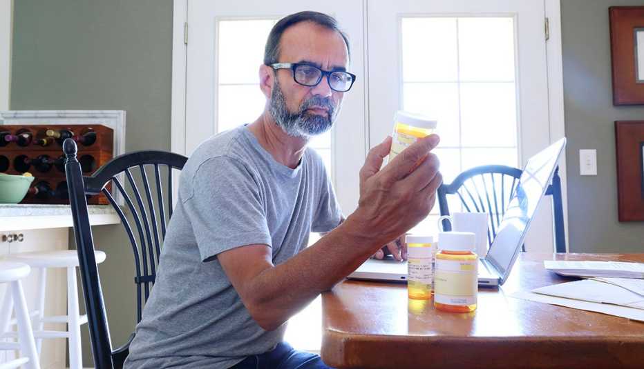 Man looking at a bottle of pills at a table