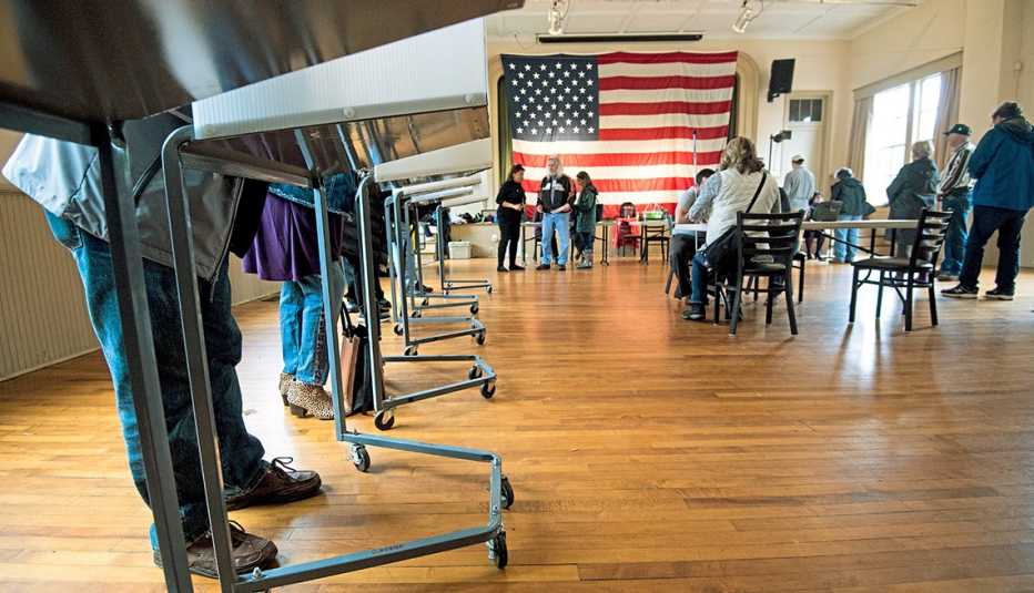 a low angle view of a polling place showing peoples legs and feet while standing in voting booths