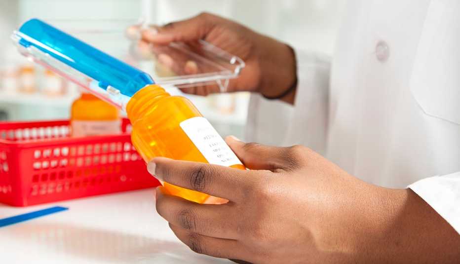 A pharmacist is filling an orange prescription drug bottle