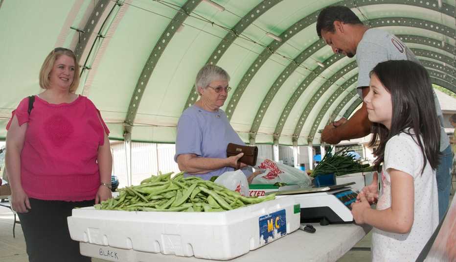 An older woman buys produce from a market