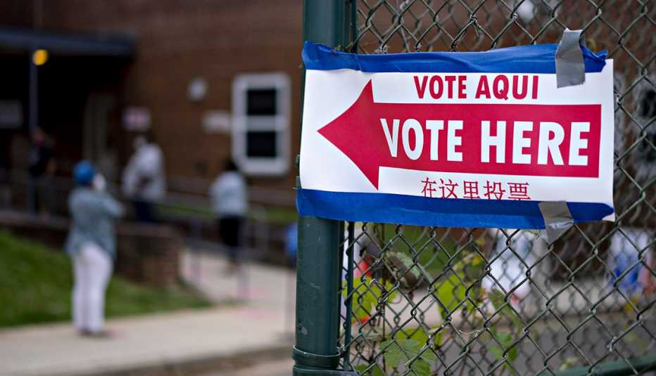 A vote here sign is attached to a fence