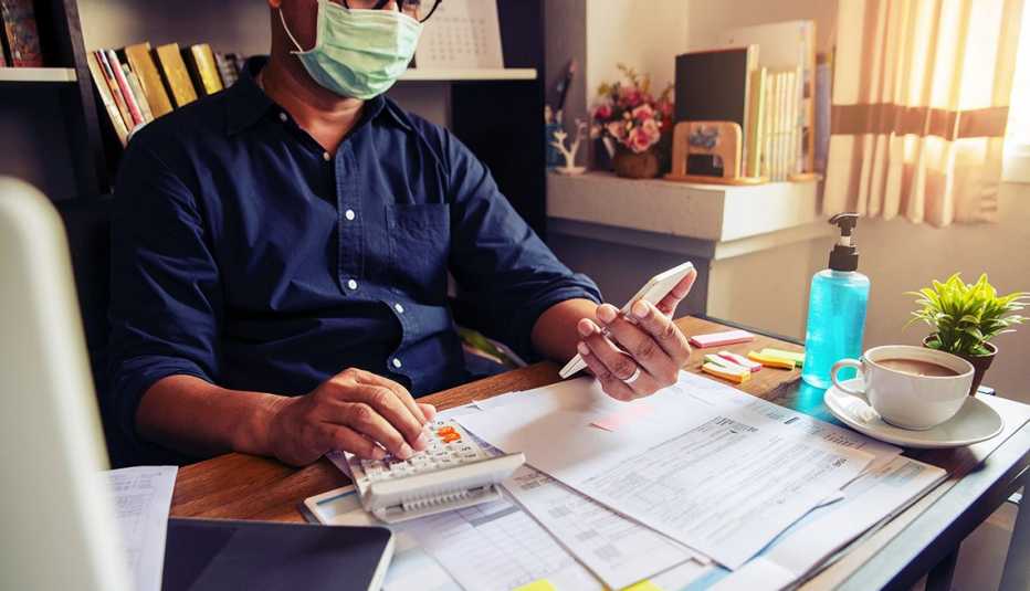 tax preparer wearing mask during pandemic calculates income tax at a desk with forms spread across surface 