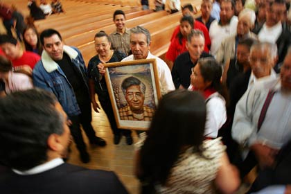 A man holds a portrait of César Chávez as Los Angeles mayoral run-off candidate Antonio Villaraigosa (l) and Christine Chávez (r), granddaughter of César, walk by in the Cathedral of Our Lady of the Angels on March 31, 2005 in Los Angeles, California. Hundreds of farm workers, labor union members, and civic and religious leaders attended the annual Mass honoring the late César E. Chávez, a life-long Catholic and founder of the United Farm Workers union.