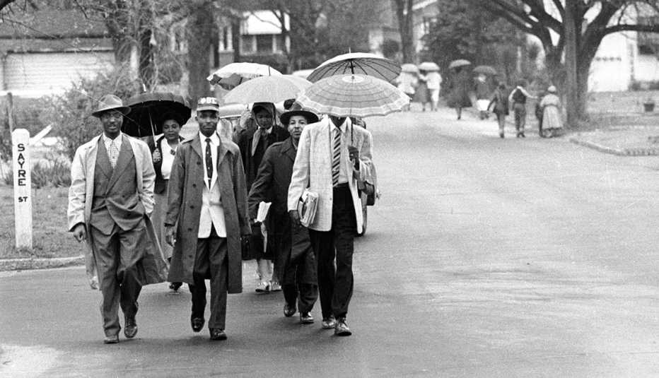 group of men holding umbrellas walking down a street during a bus boycott
