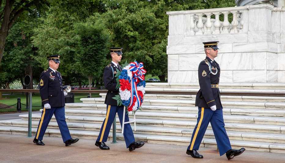 three soldiers performing a wreath laying ceremony at the tomb of the unknown soldier in arlington cemetary