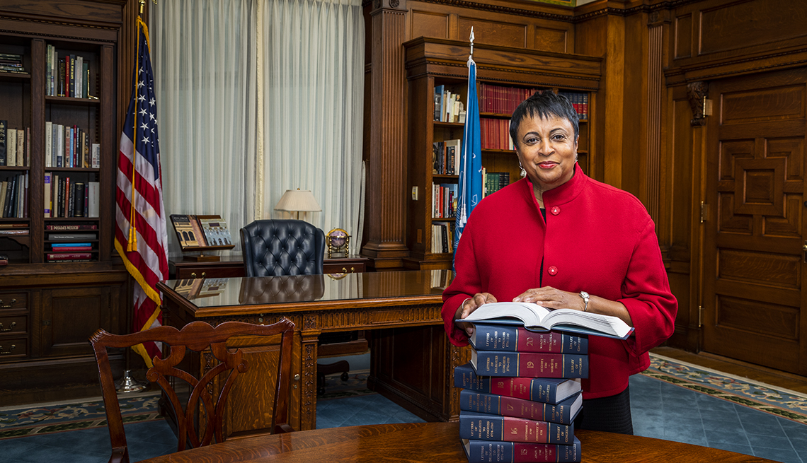 Librarian of Congress Carla Hayden stands in her office with a stack of books