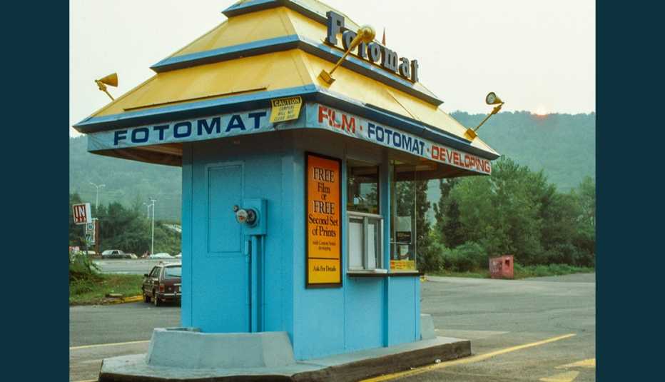 old photo of a colorful fotomat kiosk in a parking lot back in nineteen eighty three