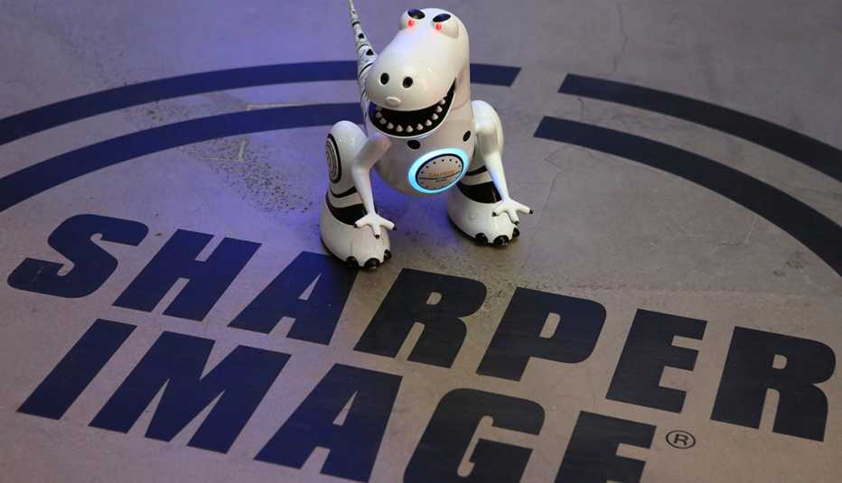 a small robot tyrannosaurus rex toy stands on top of the sharper image logo painted on a floor in a store
