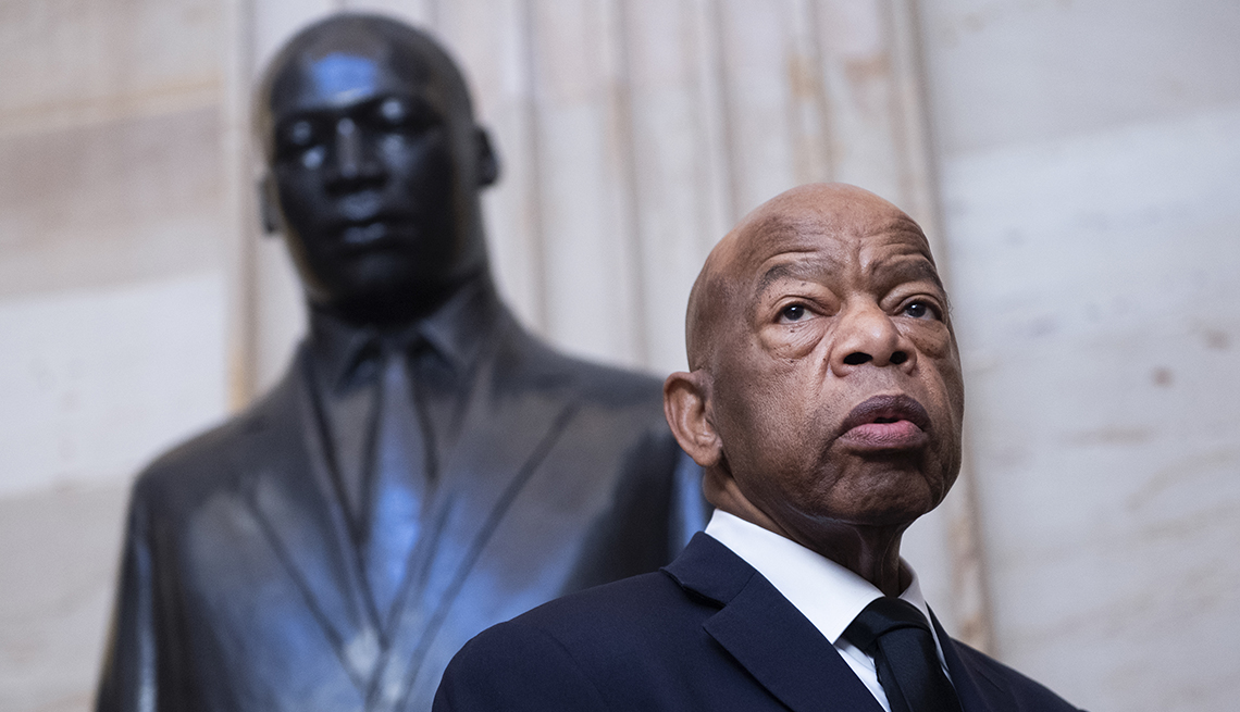 John Lewis stands in front of a statue of Martin Luther King Junior