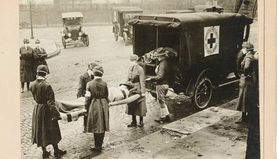 a patient on a gurney is loaded into a red cross motor corps ambulance