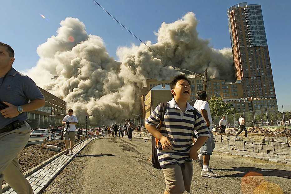 people running away as the second tower of the world trade center collapses in the distance