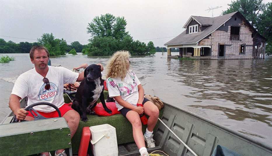 people in a flooded town on a boat after having found their stranded dog
