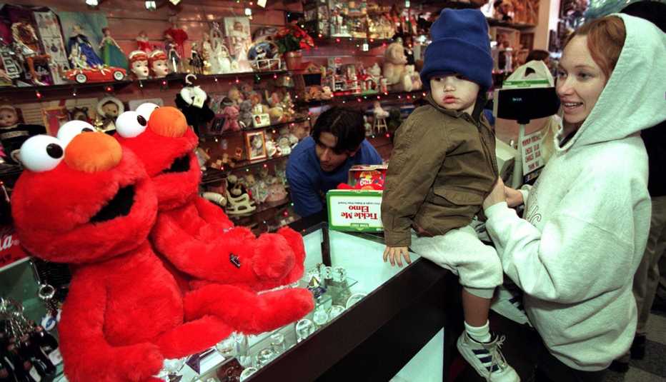 Smiling mom with toddler at store checkout counter after winning lottery ticket to buy a Tickle Me Elmo doll in 1996.
