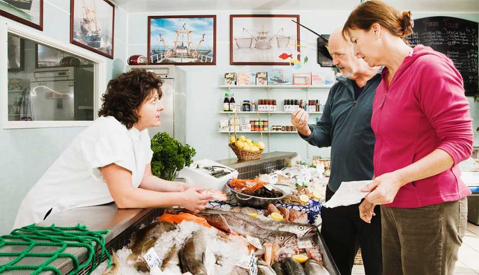 Couple talking to a fishmonger at grocery story