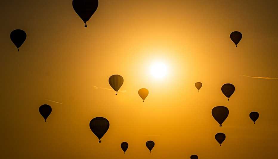 Hot air balloons pass by the sun