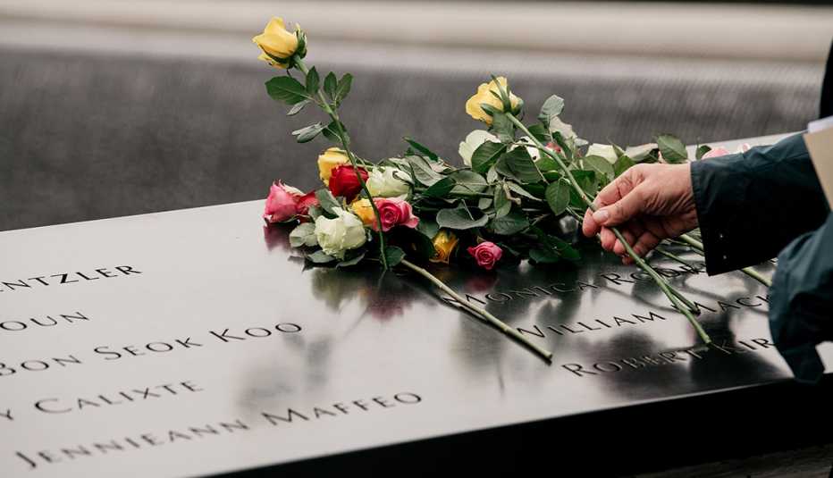 A person puts flowers on a memorial