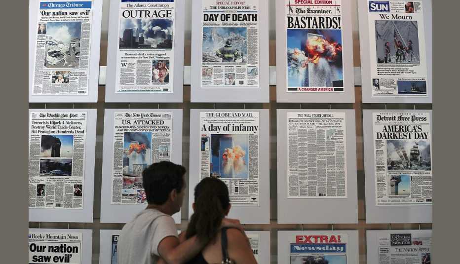 two museum visitors stand in front of a wall of newspapers from all over the world with the headlines of the nine eleven terror attacks at the newseum in washington d c in two thousand sixteen