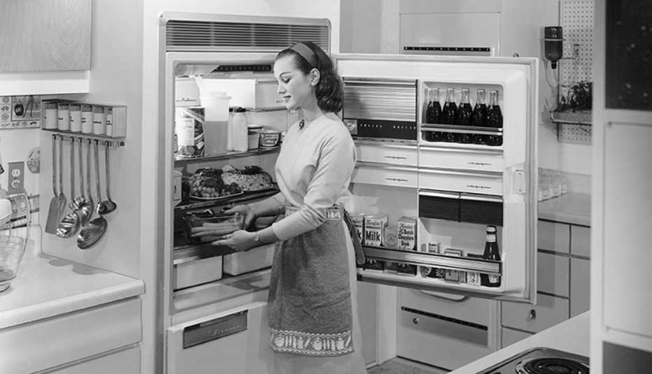 circa nineteen fifties a young housewife in a modern kitchen uses a refrigerator