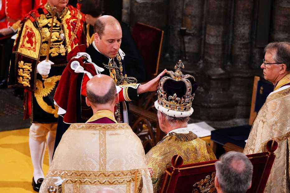 Prince William touches the St Edward's Crown on the head of his father, King Charles III.